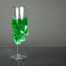 Sektglas mit grün gefärbtem Wasser - mit Luftgewehr zerschossen.